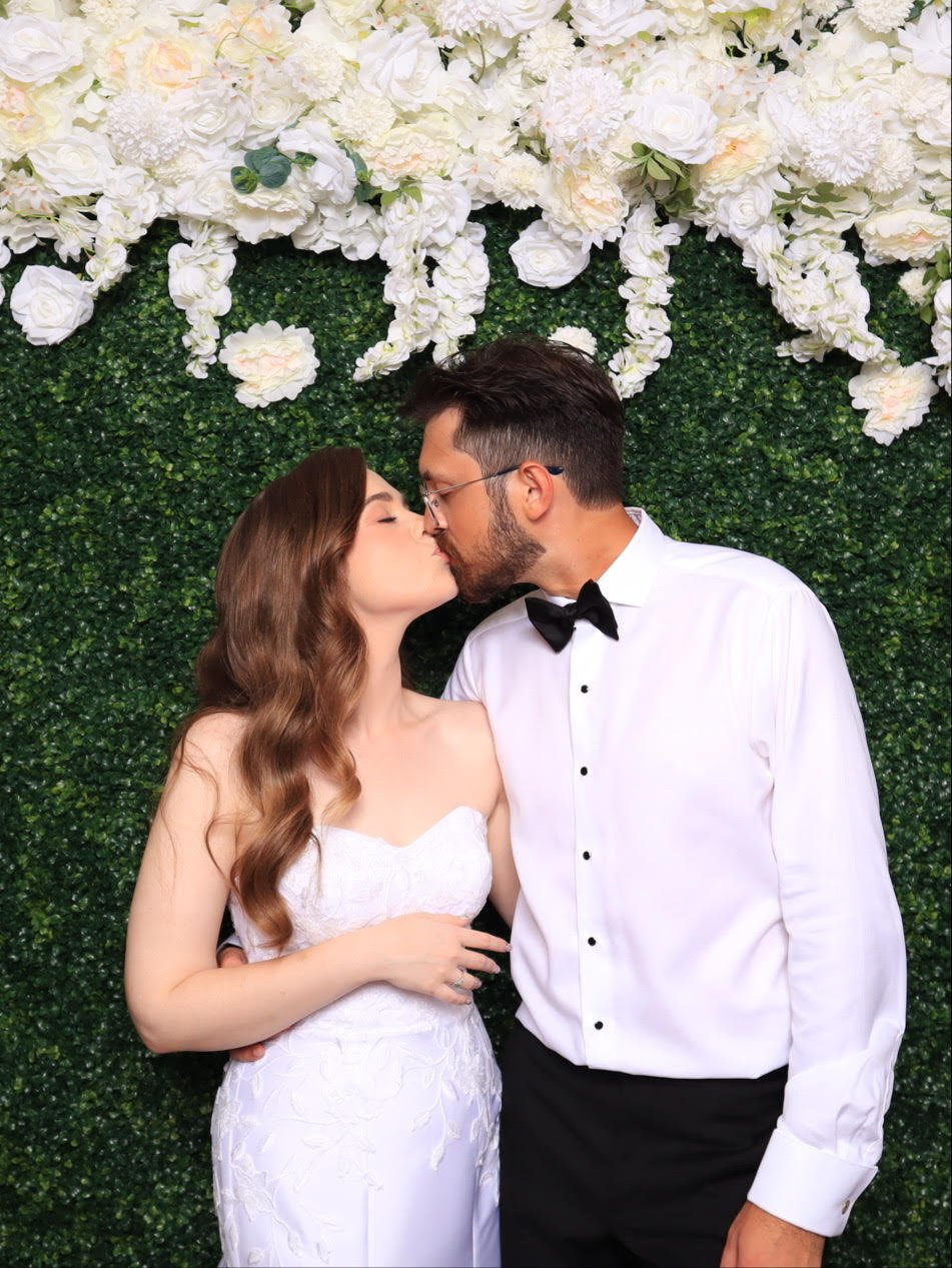 Couple sharing a kiss at the greenery wall